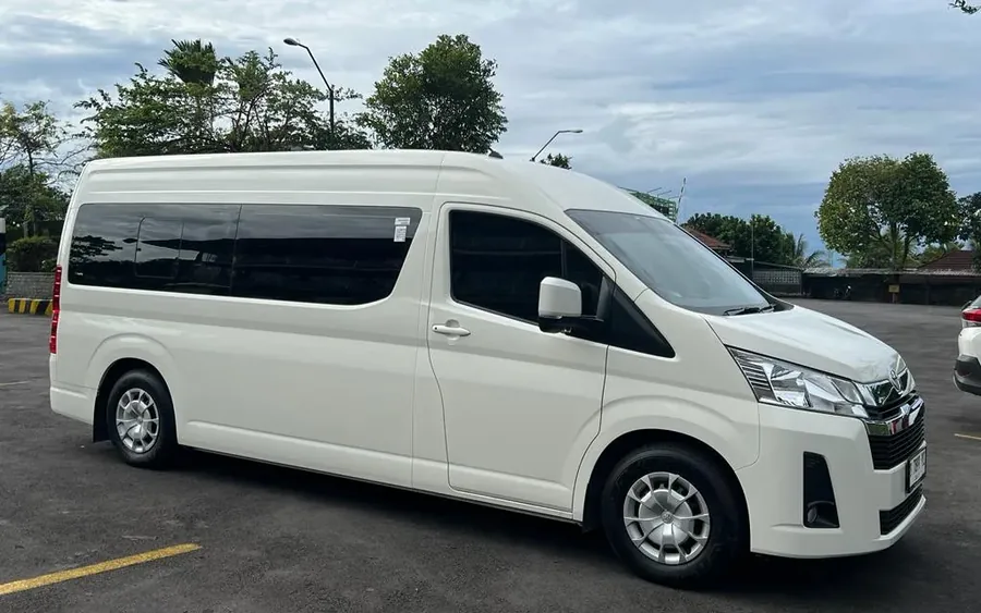 A white Toyota HiAce Premio long-wheelbase van parked on a paved road