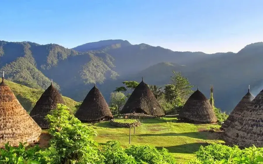 The cone-roofed houses of Wae Rebo in their highland bowl with mist over the ridges