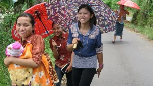 Women walking with parasols on a road near Liang Bua, Flores